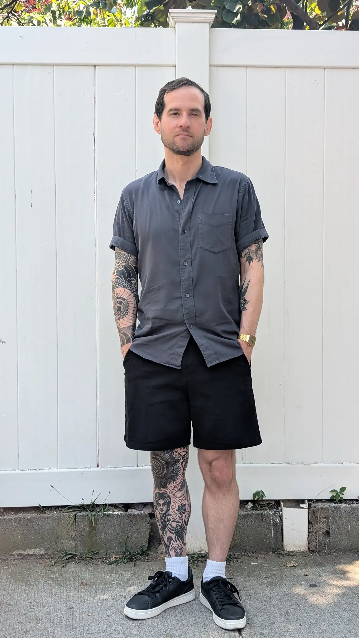 Black trouser shorts with a camp-collar button-down and black sneakers