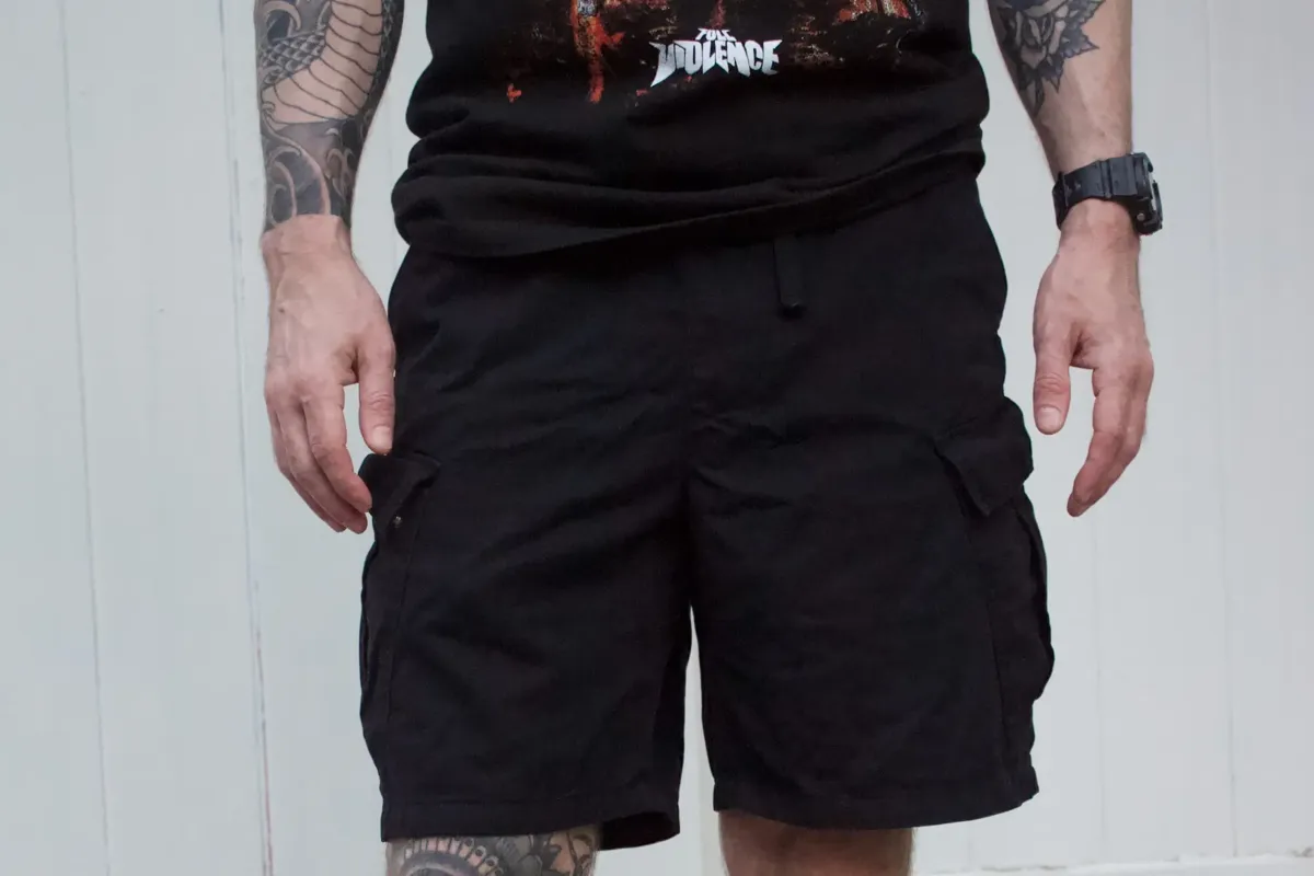 Zoomed-in shot of black cargo shorts and leg tattoos