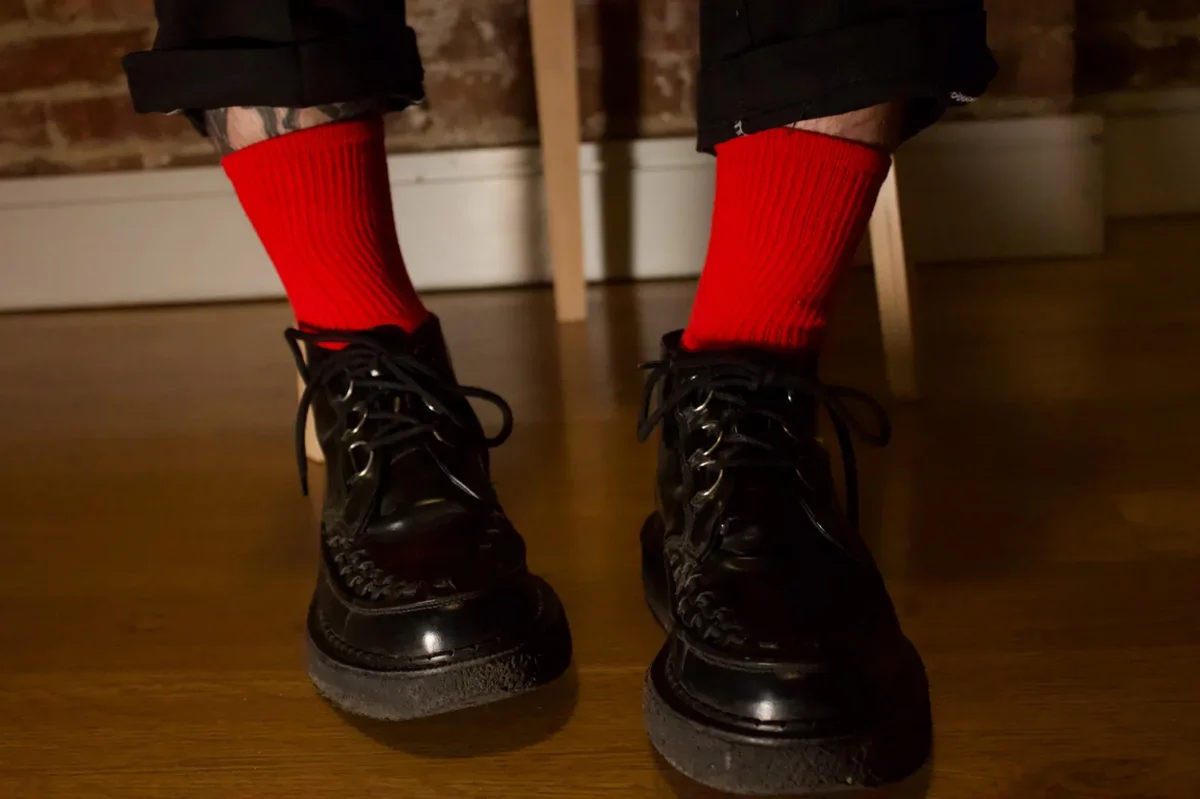Red ribbed socks styled with black creepers and cuffed pants